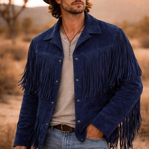 Puede incluir: Chaqueta de ante azul marino con flecos largos, usada con un sombrero de vaquero marr&oacute;n y una camisa de color claro. La chaqueta tiene un estilo western cl&aacute;sico, con botones y cuello.