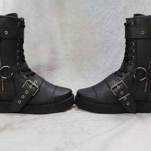 Close-up of handmade wrestling boots in black leather with detailed stitching, secure lace-up design, and adjustable buckle straps. These pro wrestling shoes are built for durability, comfort, and stability in the ring. Featuring side zippers for quick wear, they are ideal for professional wrestlers, cosplay performers, and collectors. Custom size options ensure a perfect fit for men and women. Durable leather construction makes them reliable for wrestling, stage, or costume use