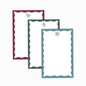 May include: Three personalized stationery sheets with scalloped edges. The sheets have different colored borders: burgundy, green, and teal. Each sheet has a different initial in a script font at the top. The paper is white.
