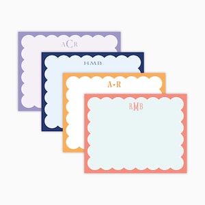 May include: Four personalized stationery cards with scalloped edges in purple, navy, orange, and coral. Each card features a different monogram in a coordinating color. The cards have a white interior for writing.