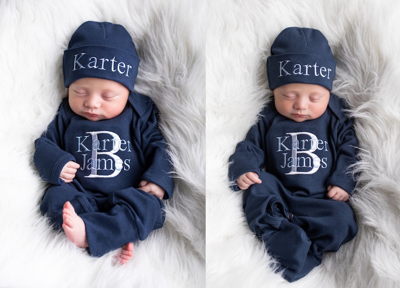 Pode incluir: Um rec&eacute;m-nascido vestindo um macac&atilde;o azul marinho com o nome "Karter James" e um grande "B" bordado na frente. O beb&ecirc; est&aacute; usando um chap&eacute;u azul marinho combinando com o nome "Karter" bordado nele.