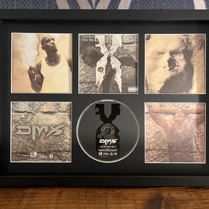 May include: Black framed display featuring a CD and album art from DMX. The artwork includes images of the artist and album covers with a stone texture background. The CD is centered, reflecting light.