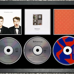 May include: Framed display featuring Pet Shop Boys album artwork and CDs. The frame includes album covers and CDs. The CDs have colourful designs. The album covers show images of the band members and album art.