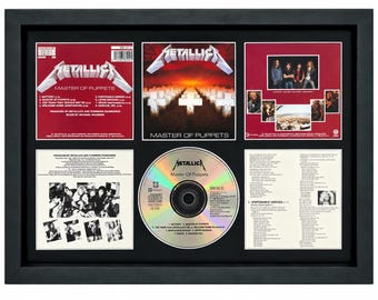 May include: A framed Metallica Master of Puppets CD display featuring the album cover art, back tracklist, band photographs, and the disc itself. The black frame contains six distinct sections showcasing the iconic red and white imagery, song titles, and production credits from the 1986 release.