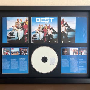 Może przedstawiać: Oprawiona płyta CD z muzyką i okładka albumu. Czarna ramka zawiera trzy okładki albumów i dwa mniejsze obrazy z tekstem, a także płytę CD. Okładka albumu przedstawia grupę osób pozujących na samochodzie.