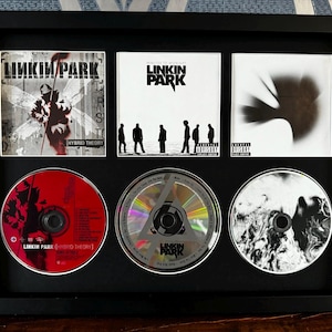 Linkin Park / Hybrid Theory / Minutes To Midnight / A Thousand Suns / Espositore da parete retrò per tre CD / Cornice non inclusa /