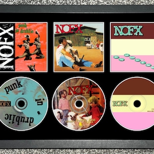 May include: A black rectangular frame containing three square NOFX album covers and three circular CDs. The covers feature Punk in Drublic, Heavy Petting Zoo, and So Long and Thanks for All the Shoes. The CDs display matching artwork and text.