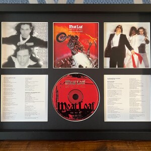 May include: Framed Meat Loaf "Bat Out of Hell" album art and CD. The frame contains a CD, album cover art, and photos of the artist. The CD is red with the album title. The album cover art features a motorcycle and flames.