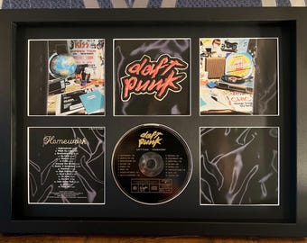 May include: Framed Daft Punk "Homework" album art and CD. The black frame surrounds the album cover art, CD, and additional images. The Daft Punk logo is in red and white. The CD is centered, with the album title and tracklist visible.