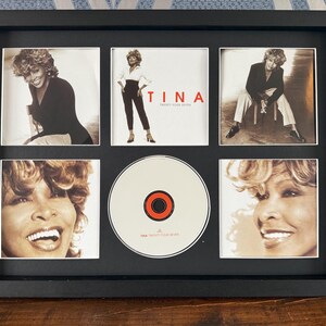 May include: Framed display featuring images of Tina Turner, including a CD. The black frame holds six images: four photos of Tina, the CD, and the album cover with the title "TINA Twenty Four Seven".