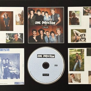 May include: A framed collage featuring images of the band One Direction. The collage includes multiple small photos of the band members, album art, and a CD. The CD is light blue with the band's name and album title, "FOUR."