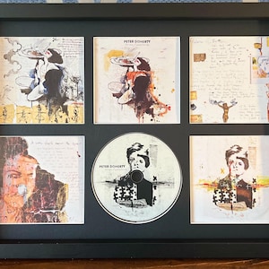 Könnte beinhalten: Gerahmtes Kunstwerk mit einer CD und fünf quadratischen Drucken. Die CD und die Drucke zeigen abstrakte Kunst und ein Porträt. Das Kunstwerk ist in einem schwarzen Rahmen präsentiert.
