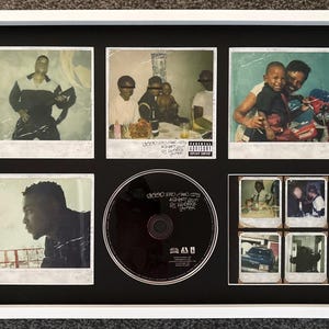 Può includere: Una cornice bianca con un passe-partout nero, sei fotografie in stile polaroid e un disco compatto circolare centrale. Il disco è nero con testo bianco che recita good kid m.A.A.d city a short film by Kendrick Lamar.
