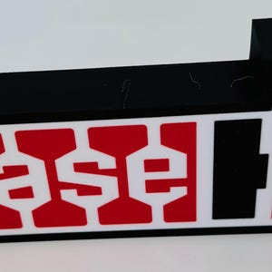 May include: A black and red Case IH logo, with the brand name in white letters on a red background. The logo is rectangular with a raised black section on top.