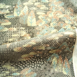 May include: A dark fabric featuring a dense, intricate pattern of geometric shapes, small floral motifs, and stylized tree-like forms in shades of black, white, muted blue, and soft orange. The textile displays a complex, layered design.