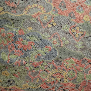 May include: A textile fabric featuring a dense, intricate pattern of overlapping cloud-like shapes and geometric grids. The design incorporates floral motifs in shades of red, olive green, yellow, and dark gray, with fine stippled textures throughout.