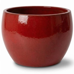 Może przedstawiać: Okrągła doniczka ceramiczna w kolorze głębokiej czerwieni z gładkim, błyszczącym wykończeniem. Doniczka posiada szeroki, okrągły otwór oraz zaokrąglony, pękaty korpus, który zwęża się lekko ku podstawie, tworząc spójną formę.