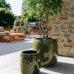 Może przedstawiać: Biały ceramiczny kubek z czarnym uchwytem i napisem "But First, Coffee" w stylu odręcznym. Kubek stoi na białej powierzchni. Kubek ma około 10 cm wysokości.