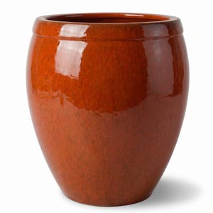 Peut inclure: Un pot de fleurs en céramique orange brûlé brillant avec un corps arrondi et bulbeux et un bord épais et lisse. La surface présente une texture subtile et marbrée avec des variations de profondeur de couleur, créant un fini réfléchissant.