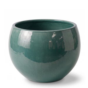Peut inclure: Un pot de fleurs en céramique bleu sarcelle profond, de forme ronde avec une finition lisse et brillante. Le récipient présente une large ouverture supérieure et un corps bombé et incurvé qui se rétrécit vers la base, reflétant la lumière.