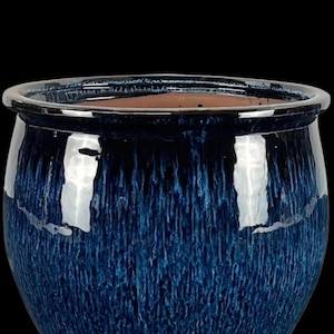 Könnte beinhalten: Ein runder, glasierter Keramik-Blumentopf in tiefblau mit glänzendem Finish. Der Topf hat eine weite Öffnung und eine leicht strukturierte Oberfläche, ideal für Pflanzen im Innen- oder Außenbereich. Der Rand ist in einem dunkleren Blauton gehalten.