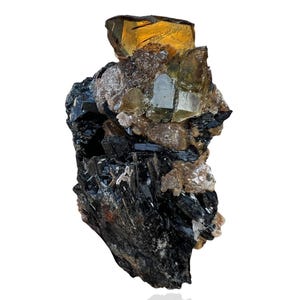 May include: A natural mineral specimen featuring a cluster of black tourmaline crystals with a large, golden-yellow topaz crystal on top. The topaz has a faceted appearance, and the overall composition is set against a white background.