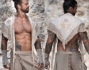 May include: A person wearing a white crocheted shawl with a geometric design. The shawl is tied around the neck and hangs down the front of the body. The person is wearing beige pants with a decorative waistband.