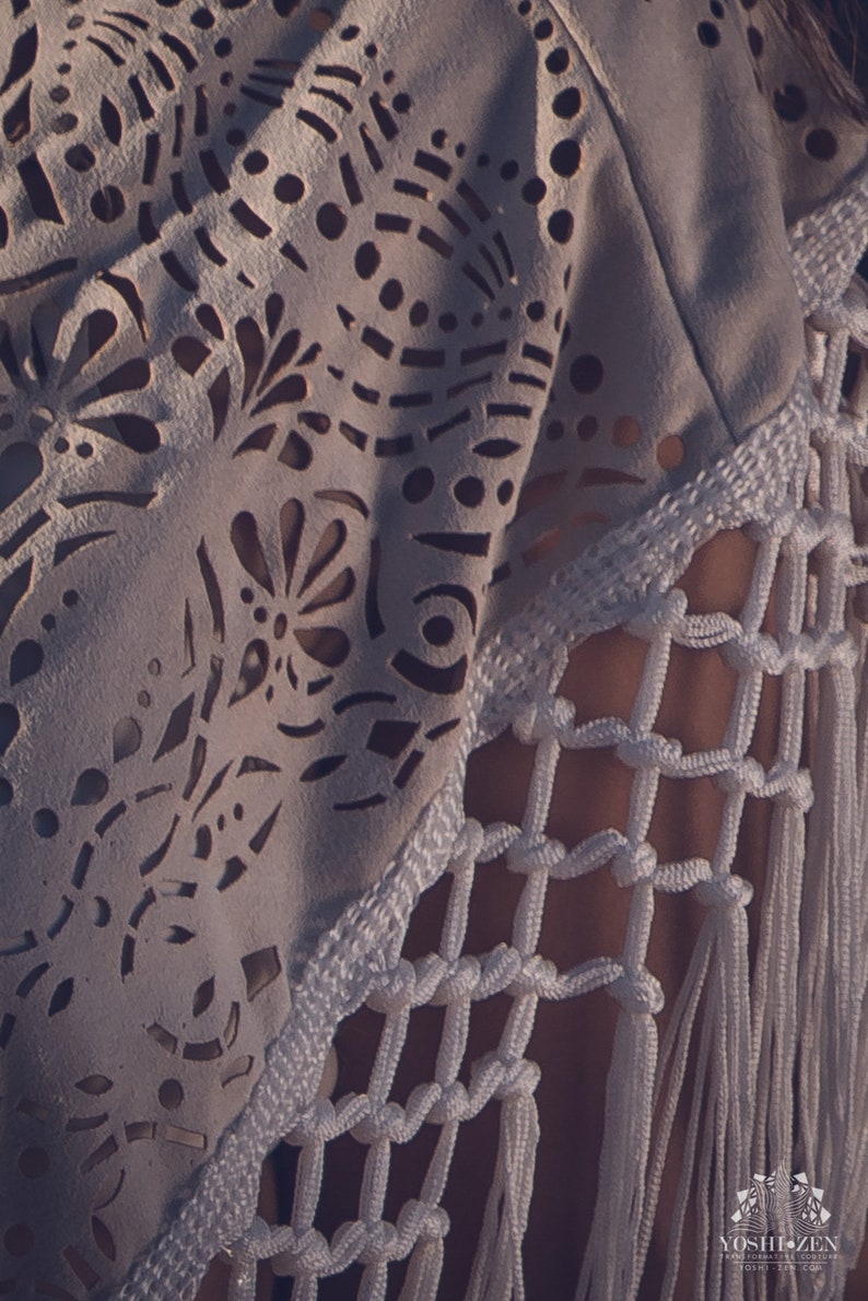May include: White crochet top with a delicate lace pattern and fringe detail. The top is made of a lightweight fabric and has a relaxed fit.
