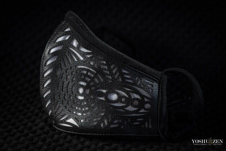 May include: A black face mask with a silver geometric pattern. The mask is made of a soft, breathable fabric and has a comfortable fit.