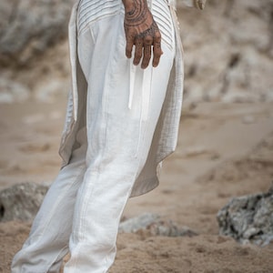 K&ouml;nnte beinhalten: Wei&szlig;e Leinenhose mit Kordelzugbund und langem, flie&szlig;endem Fall hinten. Die Hose hat eine lockere Passform und ist perfekt f&uuml;r einen l&auml;ssigen, bohemian Look.