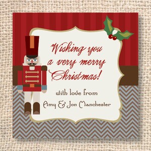 May include: A square Christmas card with a red and brown striped background, a nutcracker illustration, and the text "Wishing you a very merry Christmas!" in a decorative font. The card also includes a holly sprig and the names "Amy & Jon Manchester".