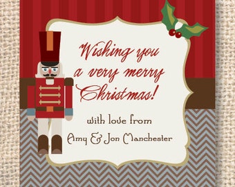 Peut inclure: Carte de Noël carrée avec un fond à rayures rouges et marron, une illustration de casse-noisette et le texte "Wishing you a very merry Christmas!" dans une police décorative. La carte comprend également une branche de houx et les noms "Amy & Jon Manchester".