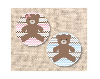 May include: Two round stickers with brown teddy bears on a chevron patterned background. One sticker has a pink and gray chevron pattern and the other has a blue and gray chevron pattern.