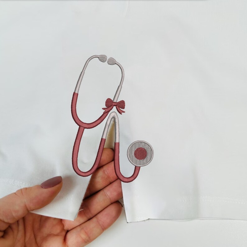 May include: Embroidered stethoscope design in burgundy and silver, with a small bow detail. The medical instrument is on a white background. The stethoscope is a symbol of healthcare and medicine.