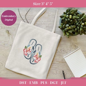 Op de afbeelding: Een crèmekleurige draagtas met een ontwerp van blauwe en grijze slippers versierd met rode en witte hibiscusbloemen. De tas heeft witte handvatten en de tekst "Embroidery Digital" in een roze cirkel. De afmeting is 7,6 cm 10,2 cm 12,7 cm.