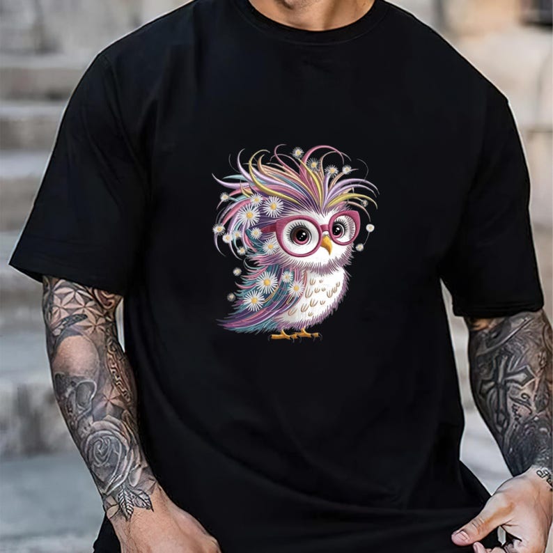 May include: Black t-shirt featuring a colorful cartoon owl wearing pink glasses and adorned with daisies. The owl has a rainbow-colored head of hair. The design is centered on the shirt.