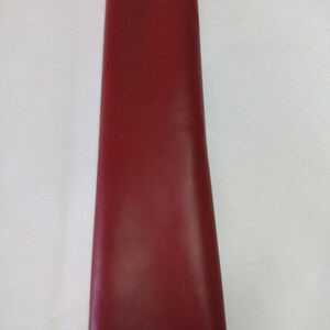 Peut inclure: Une longue bande verticale de mat&eacute;riau rouge fonc&eacute;, lisse et uni. La surface semble uniforme et mate, s'&eacute;tendant du haut vers le bas du cadre. Les bords sont droits et nets, mettant en valeur une couleur cramoisie audacieuse et constante.