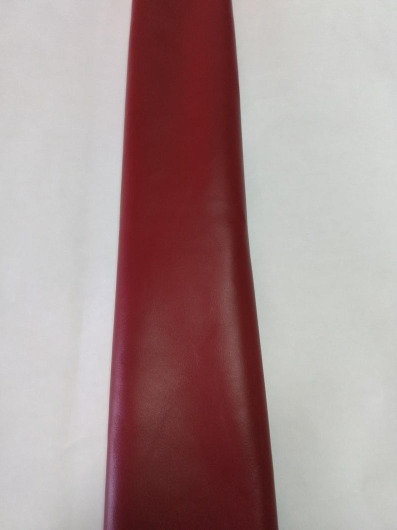 Peut inclure: Une longue bande verticale de mat&eacute;riau rouge fonc&eacute;, lisse et uni. La surface semble uniforme et mate, s'&eacute;tendant du haut vers le bas du cadre. Les bords sont droits et nets, mettant en valeur une couleur cramoisie audacieuse et constante.