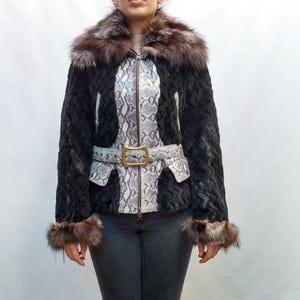 May include: A black faux fur jacket with a snakeskin pattern down the center and a matching belt. The jacket has a fur collar and fur cuffs. The belt has a gold-colored buckle. The jacket is zipped up.