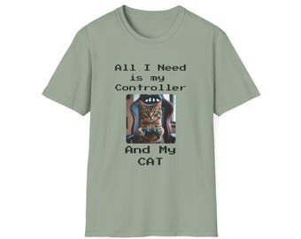 May include: Sage green t-shirt featuring a cat holding a controller, with the text "All I Need is my Controller And My CAT". The cat is sitting in a gaming chair. The shirt is a short-sleeved crew neck.