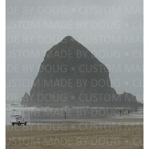 Könnte beinhalten: Graue Küstenlandschaft mit einem großen Felsen auf einem Sandstrand. Ein weißer Transporter und mehrere Personen sind am Strand zu sehen. Der Text "DE BY DOUG • CUSTOM MADE" wiederholt sich.