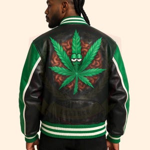 Op de afbeelding: Zwarte en groene leren jas met een groot, cartoonachtig groen cannabisblad-ontwerp op de rug. De jas heeft groene mouwen met witte strepen en een wit en groen gestreepte kraag en manchetten. Het woord "LEATHER" staat op de onderkant van de jas.