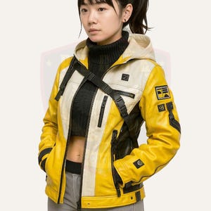 Peut inclure: Une veste en cuir jaune et blanche avec une fermeture éclair noire et une sangle noire. La veste a une capuche et plusieurs poches.