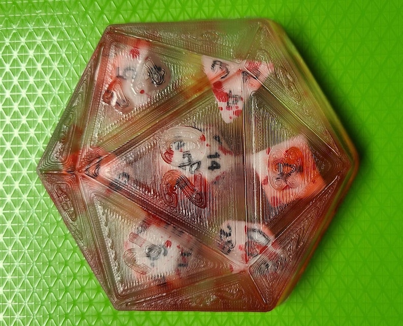 K&ouml;nnte beinhalten: Ein transparenter, mehrseitiger W&uuml;rfel mit roten und wei&szlig;en Markierungen. Der W&uuml;rfel besteht aus einem durchsichtigen Material und hat auf jeder Seite eine Zahl.