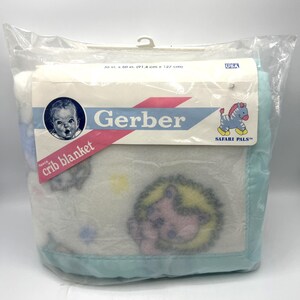 May include: A white fleece crib blanket with a light blue border, featuring a printed pattern of colorful animals. The packaging is labeled Gerber Safari Pals and measures 36 in. x 50 in. The blanket is enclosed in a clear plastic bag.