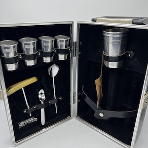 May include: A white ceramic mug with a black handle and the text "But First, Coffee" in a bold, black font. The mug is set against a neutral background, highlighting its simple design.