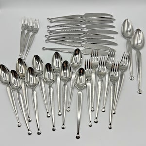 May include: A white ceramic mug with a black handle and the text "But First, Coffee" in a bold, black font. The mug is filled with a dark liquid, likely coffee, and sits on a light-colored surface.