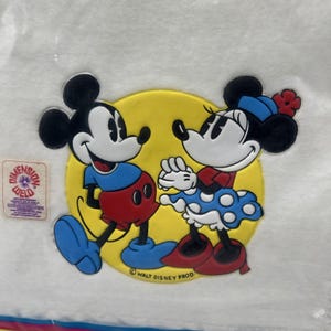 Pu&ograve; includere: Un adesivo Dimension Weld con Topolino e Minnie. Topolino indossa pantaloncini rossi, scarpe blu e una camicia blu. Minnie indossa una gonna a pois blu, scarpe rosse e un cappello blu con un fiore rosso. Lo sfondo &egrave; un cerchio giallo.
