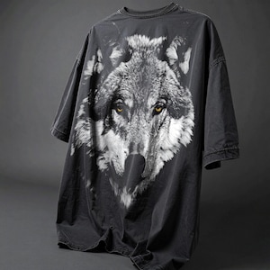 May include: A black t-shirt with a large, detailed image of a wolf's face printed on the front. The wolf's eyes are a bright yellow.