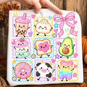 Könnte beinhalten: Ein weißes Stoffquadrat mit einem Raster aus bunten Cartoon-Illustrationen, darunter ein Boba-Tee, ein Knödel, eine rosa Vichy-Schleife, ein Eis mit drei Kugeln, Toast mit Marmelade, eine Avocado, ein Donut, eine Kuh und ein regenbogenfarbener Gummibär.